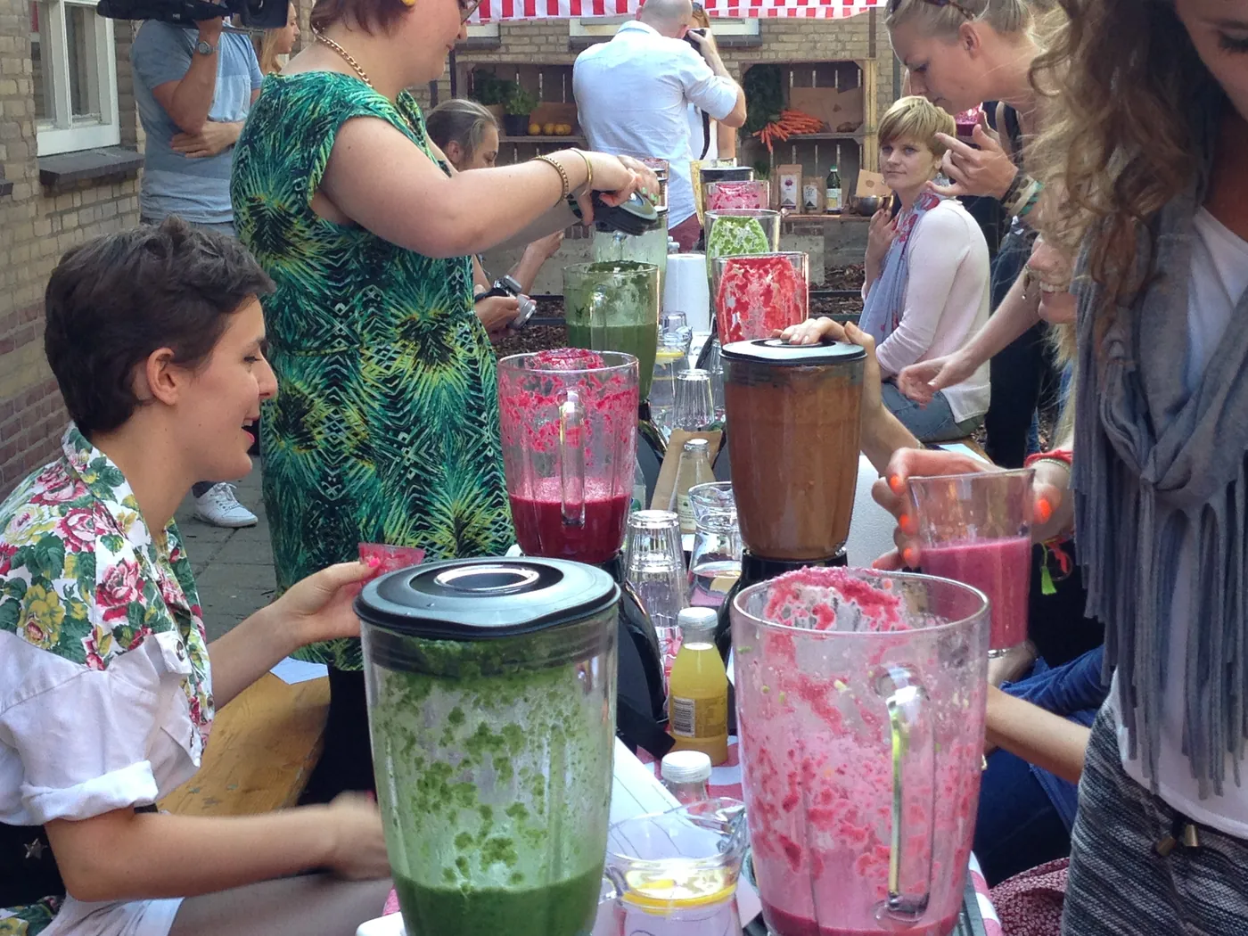 Deelnemers maken samen kleurrijke smoothies met blenders vol groente en fruit